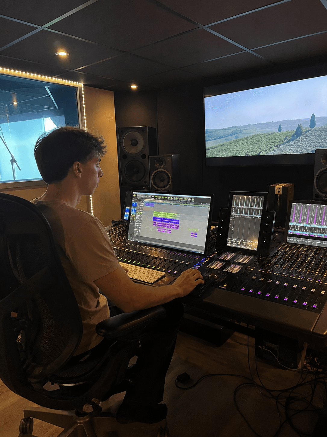 Arthur Thomas en régie de post-production sonore, devant une console de mixage et deux écrans.